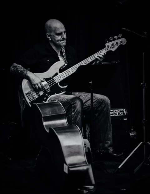Jason Malmberg playing electric bass on stage, black and white photo